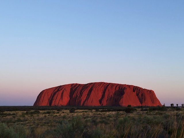夕日に照らされ赤く染まるウルル(エアーズロック)。オーストラリアの世界遺産で楽しむサンセットの風景